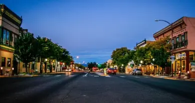 Main Street in downtown Montrose, Colorado at dusk with historic storefronts lit up
