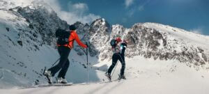 Two people cross country skiing in the snowy mountains